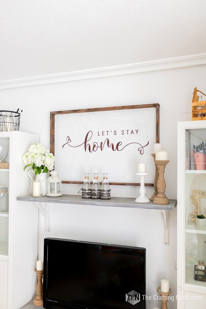 Rustic oversize wood sign on the wall with Let's Stay Home sentiment.