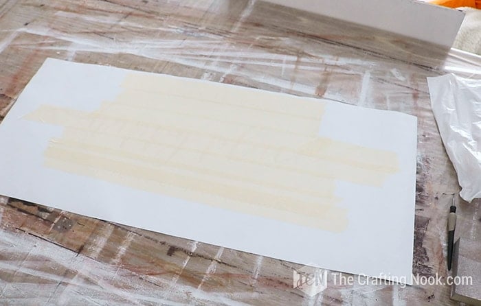 Applying transfer tape or masking tape to transfer the stencil to the wood board.