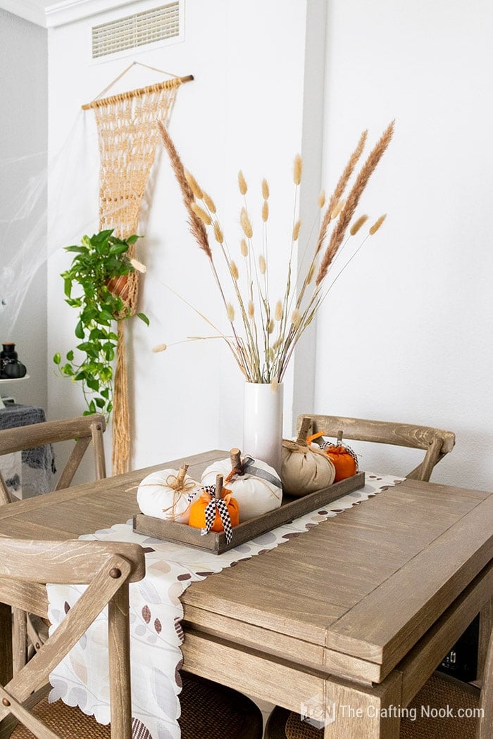 dining table, with a tray on a cute fall table runner with a vase filled with fake pampas grass and bunny tails surrounded