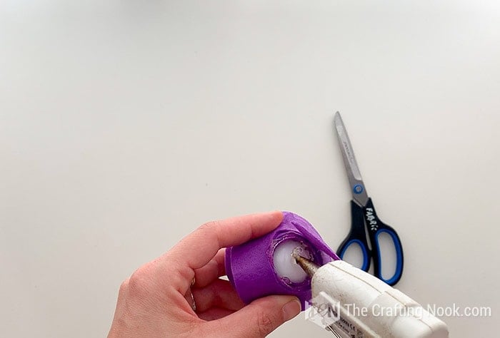 applying hot glue to the base of the plastic eye