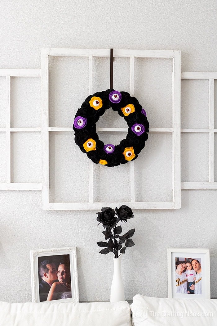 The spooky Halloween Wreath made with spooky eyeballs hanging on the window frame of the living room