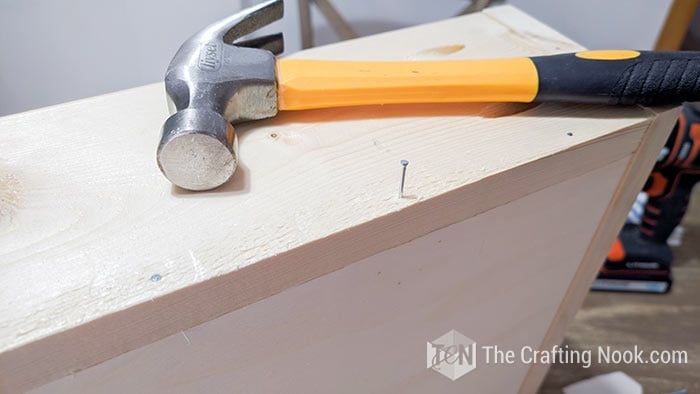 hammer and nail in position to be placed in the drawer
