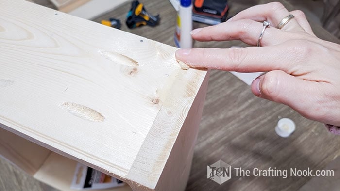 Applying wood putty on the holes and cracks of the drawer