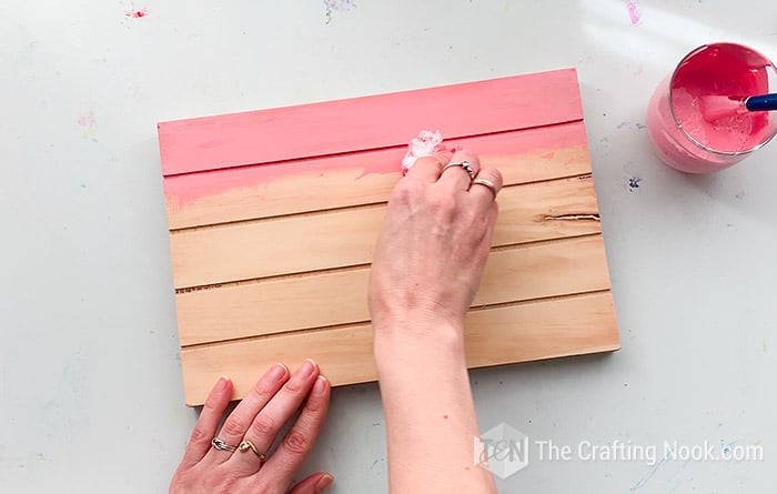 rubbing the pink paint on the mini pallet with a piece of cloth