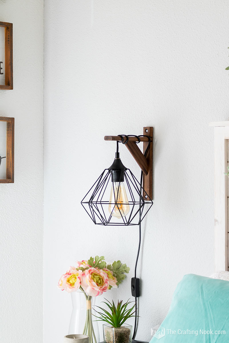 Cute view od the sconce light above the nightstand with flowers and candles