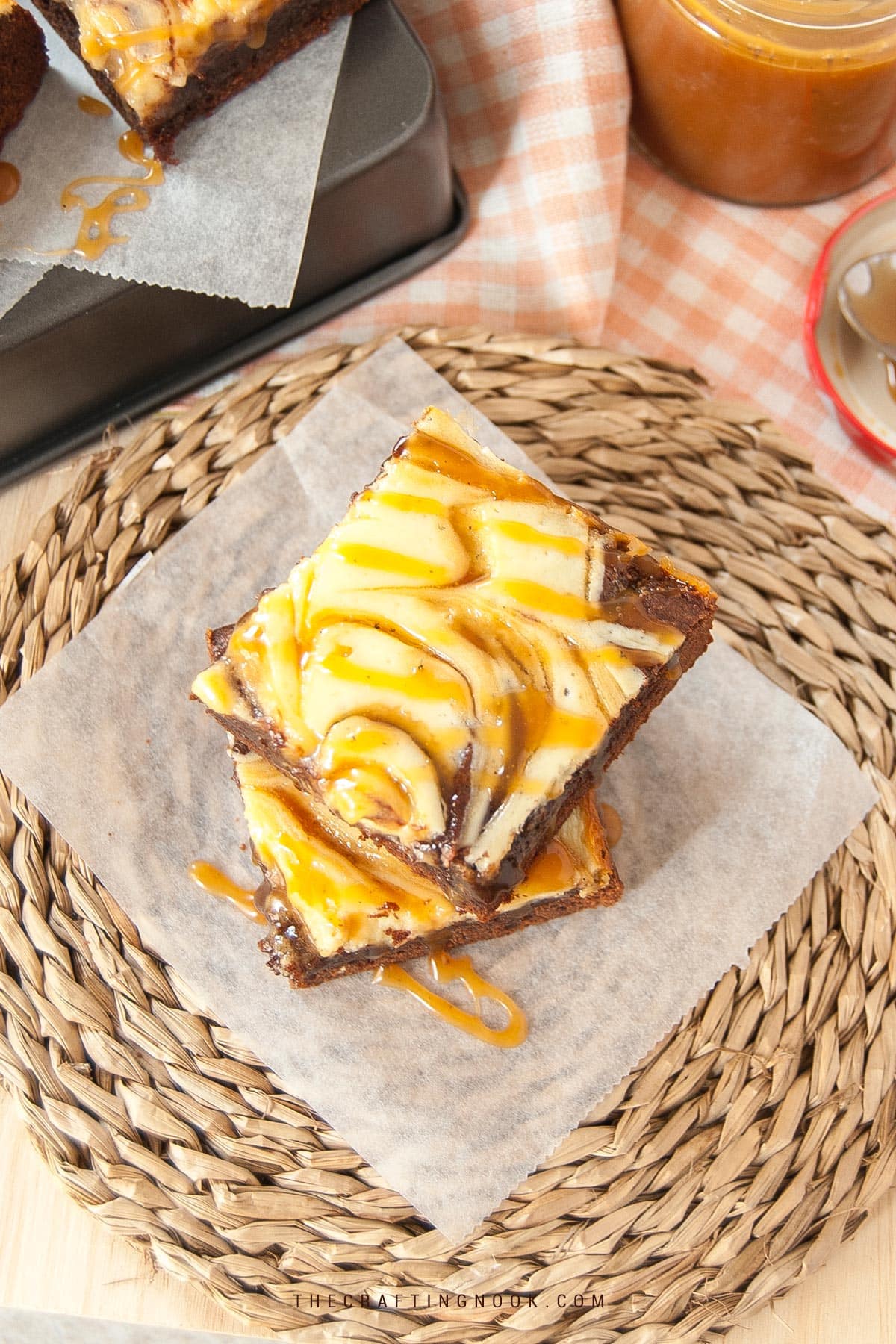 stack of two salted caramel cheesecake brownies on parchment with a drizzle of caramel sauce cover image