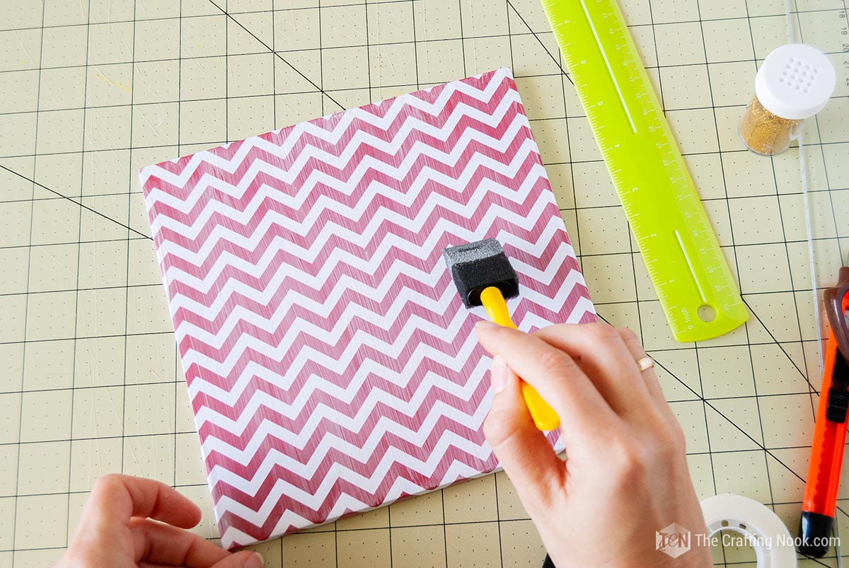 applying a sealant coat of mod podge over the surface of the Patterned paper