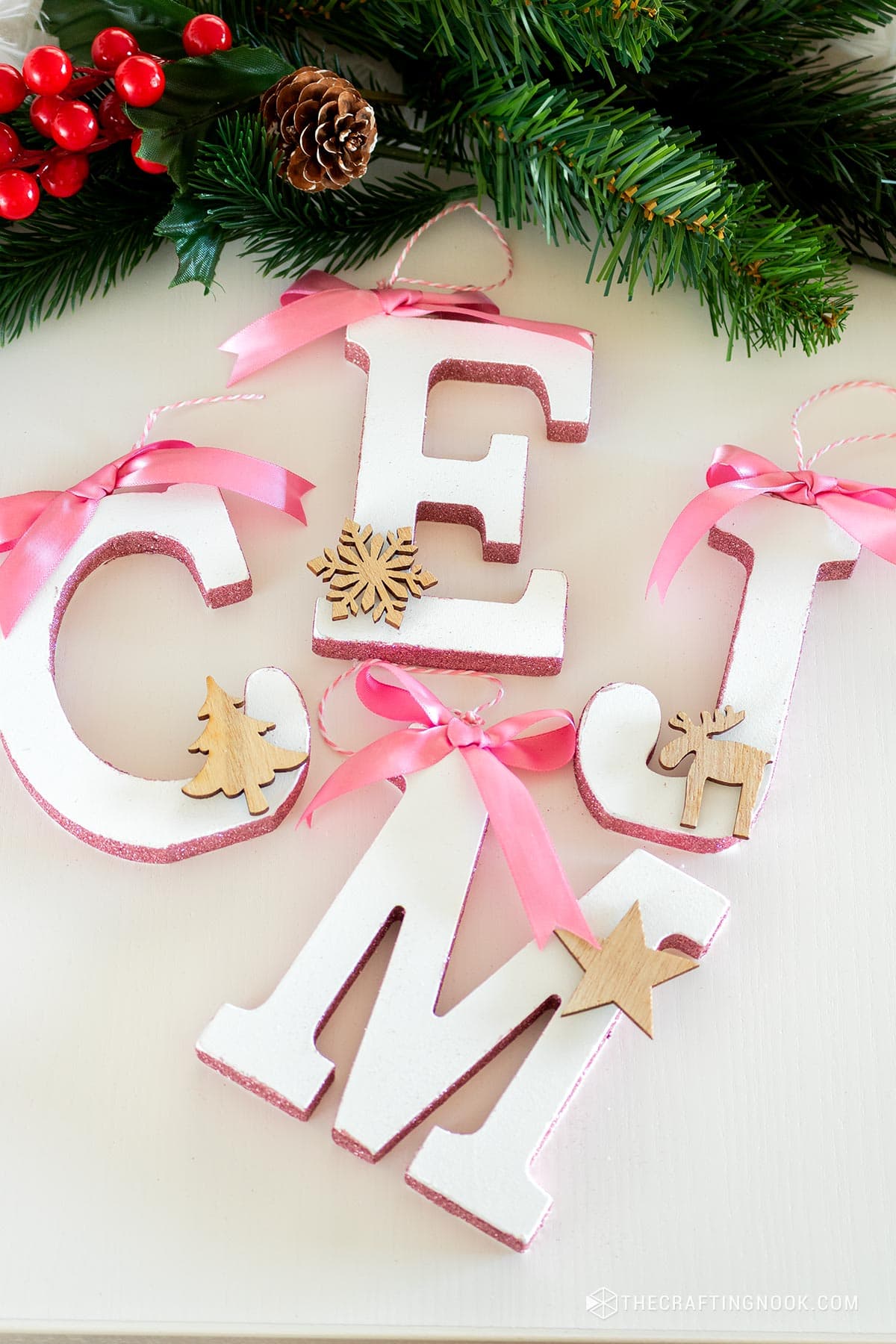 Closeup DIY Initial Letter Ornaments with Glitter on the side edges hanging on a table with greenery letter M, C, O, E, and J.