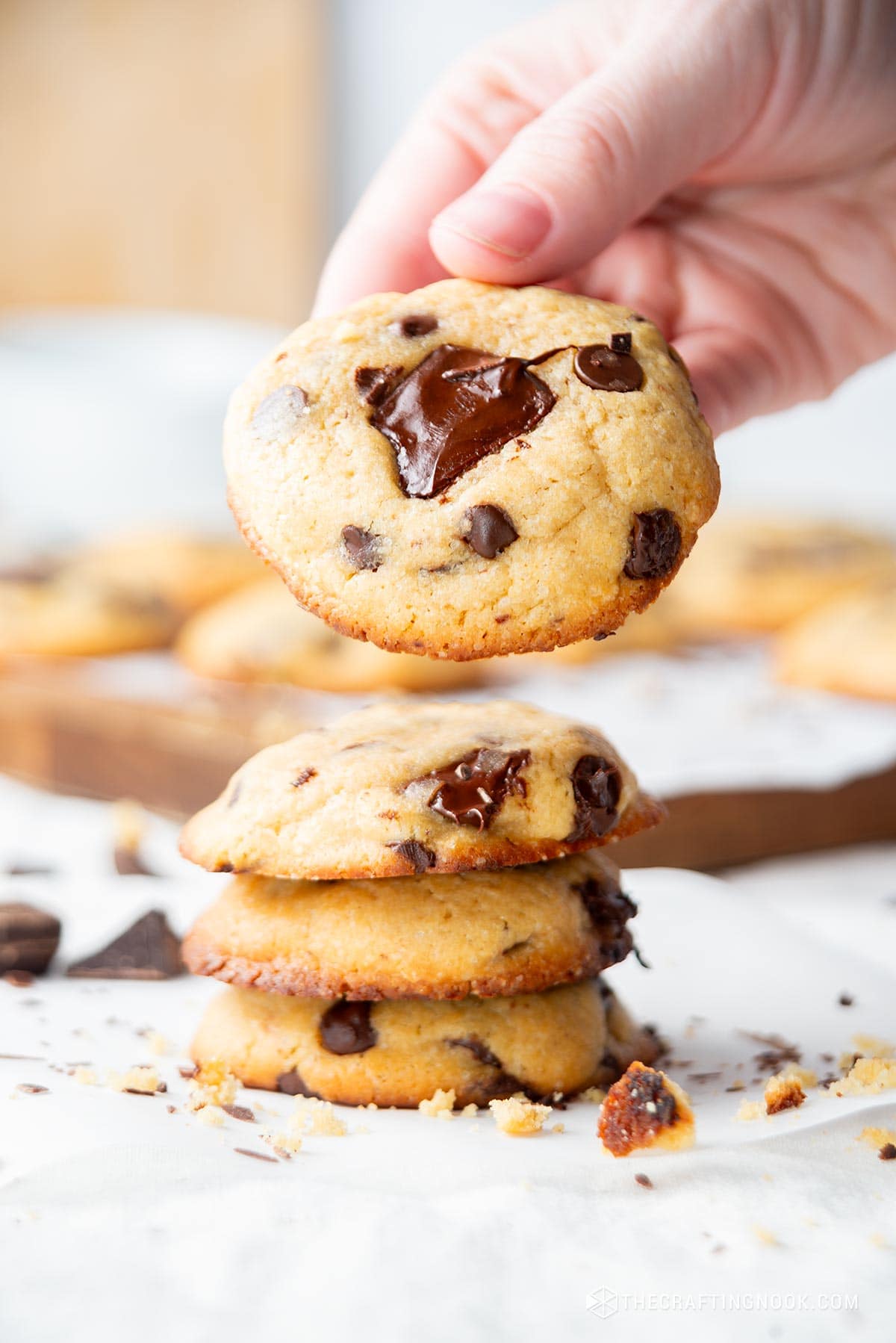 Small Batch Chocolate Chip Cookies Recipe. The cookies are piled up and the last one i hold by a hand.