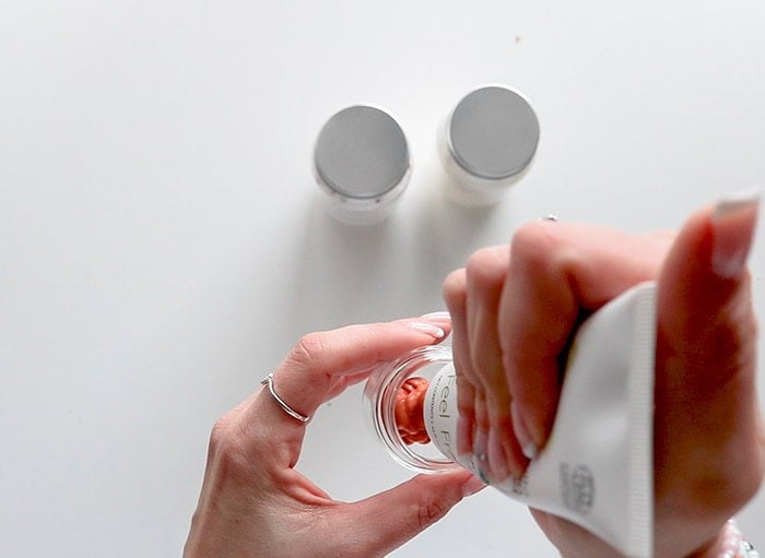 pouring face mask into a small glass jar
