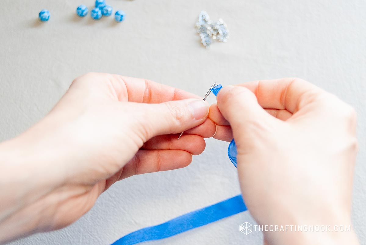 View of inserting into the needle to thread about 2 inches of ribbon through the hole.
