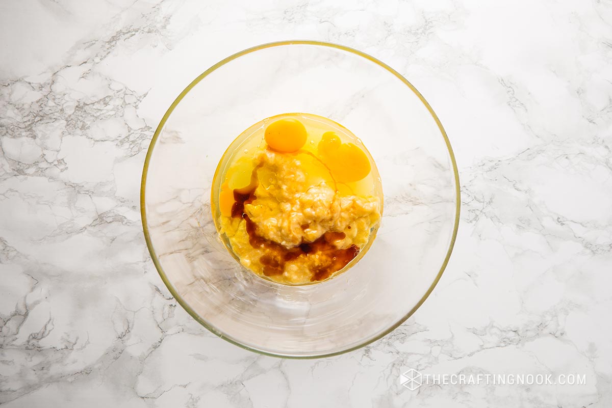 top view of sugar, mashed bananas, oil, eggs, and vanilla extract in a bowl