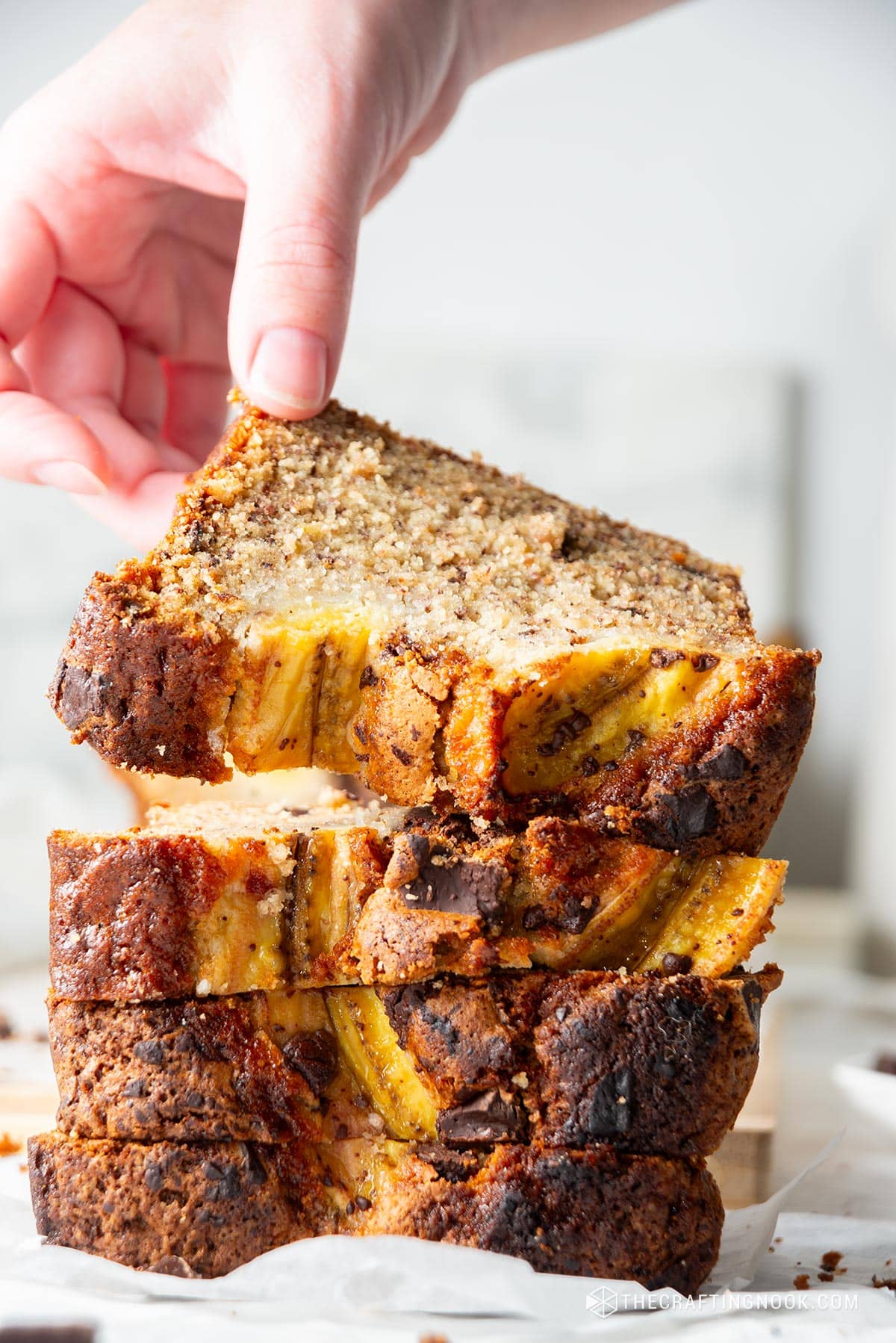 a hand picking up a loaf of Chocolate Chunk Banana Bread Recipe