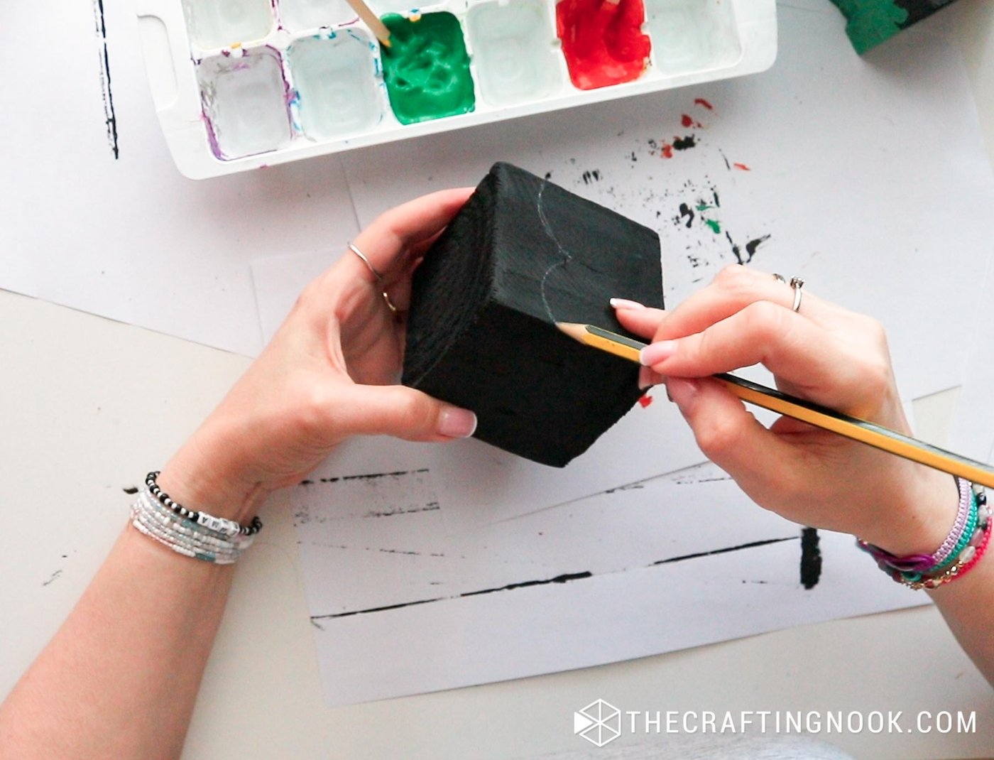 top view drawing with a pencil the shape of Dracula's face on a piece of wood painted in black