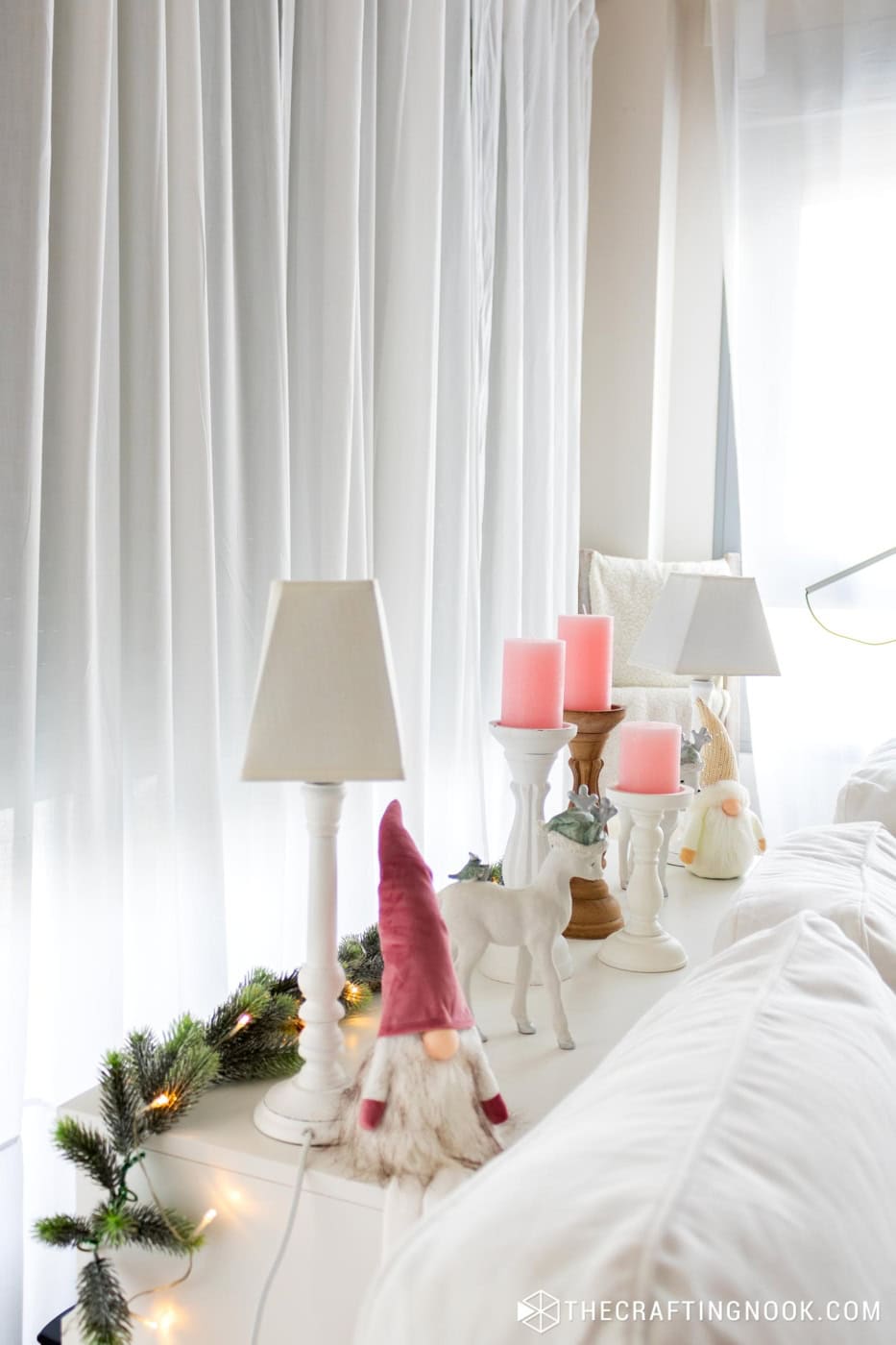 close view of the furniture behind the sofa with the Christmas nome decoration in pink and neutral colors
