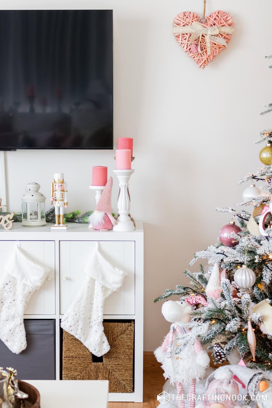 closed image of the decoration of the television cabinet with pink candles and part of the decorated Christmas tree
