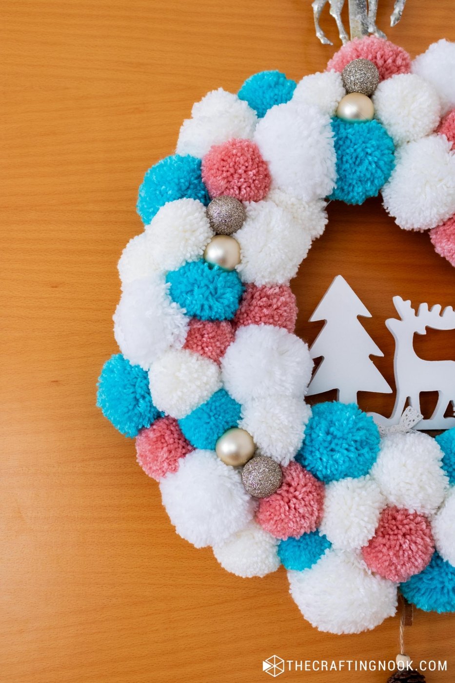 View of half of the DIY White, Pink and Blue Pompom Wreath for Christmas hanging on the door.