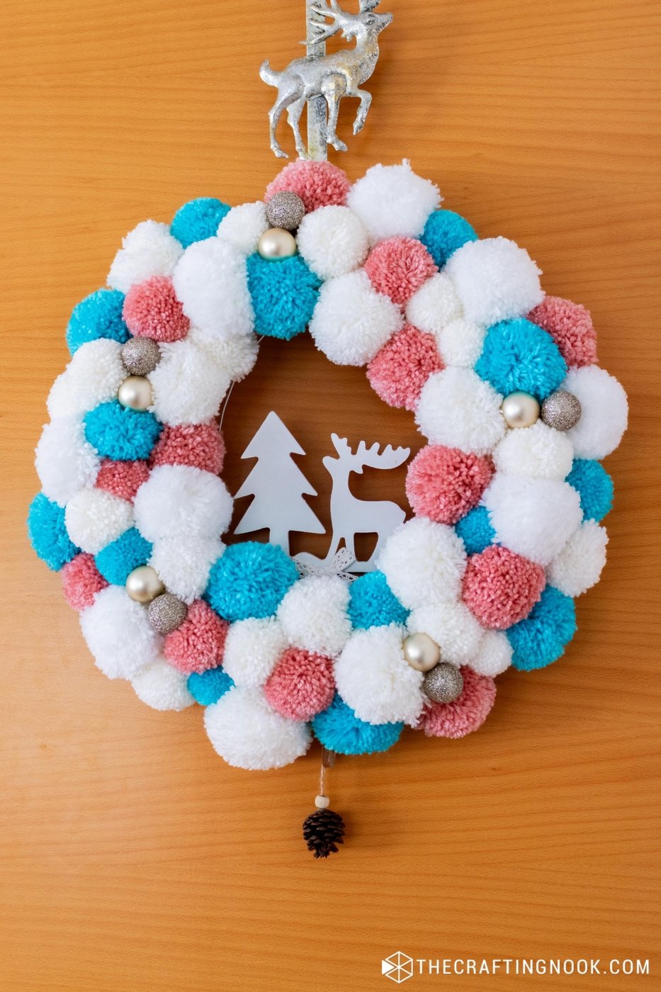 Closer view of DIY White, Pink and Blue Pompom Wreath for Christmas hanging on the door.