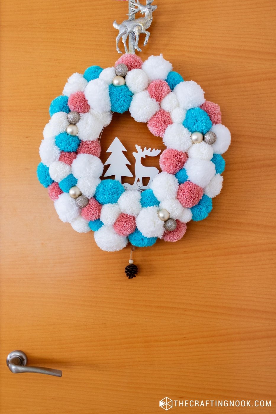 View from far away of White, Pink and Blue Pompom Wreath for Christmas hanging on the door