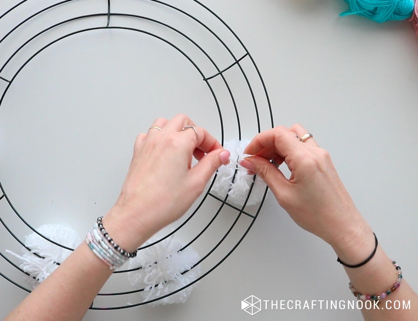 top image tying the white pompoms separately on the wire wreath
