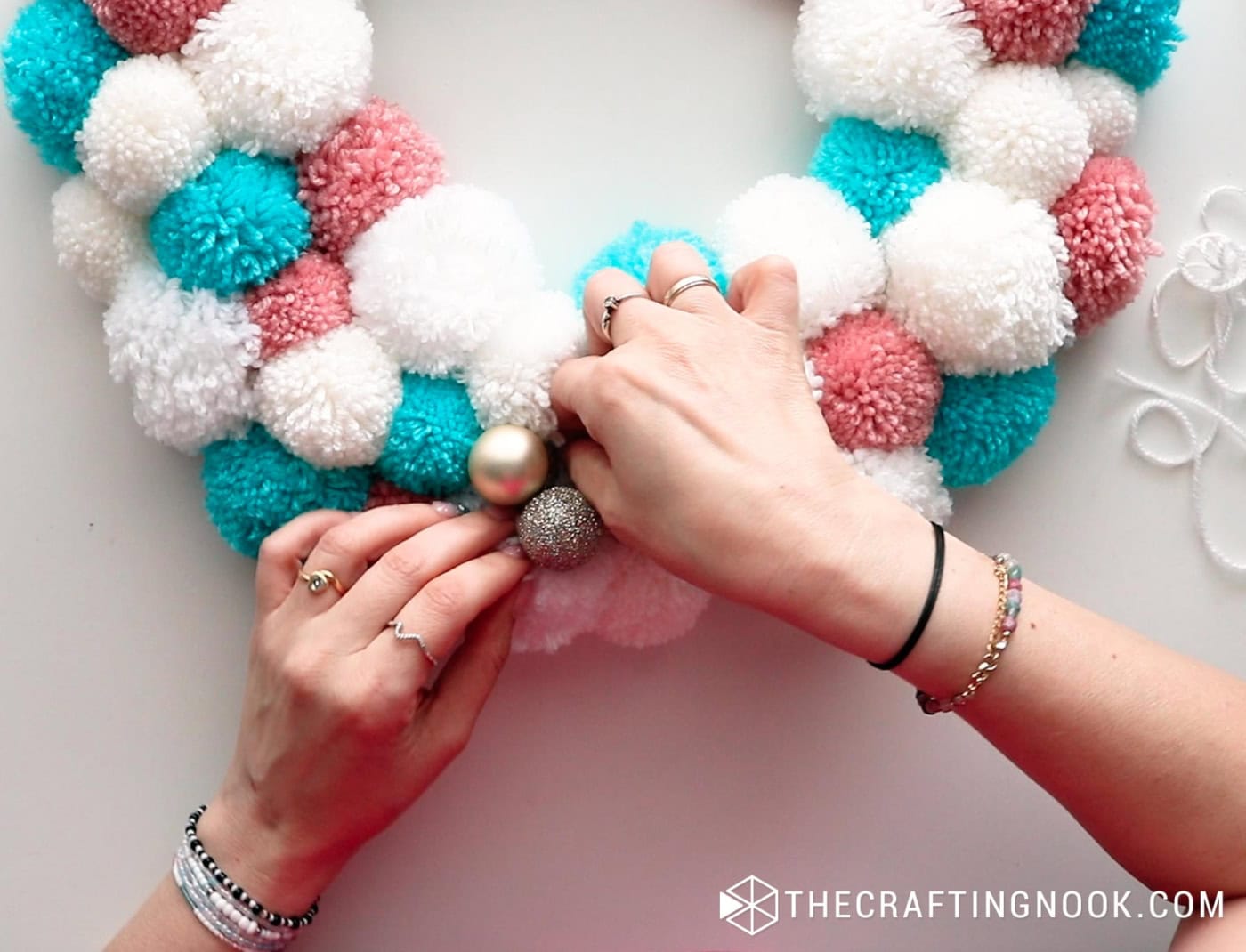 top image placing the ornaments on the pompom garland
