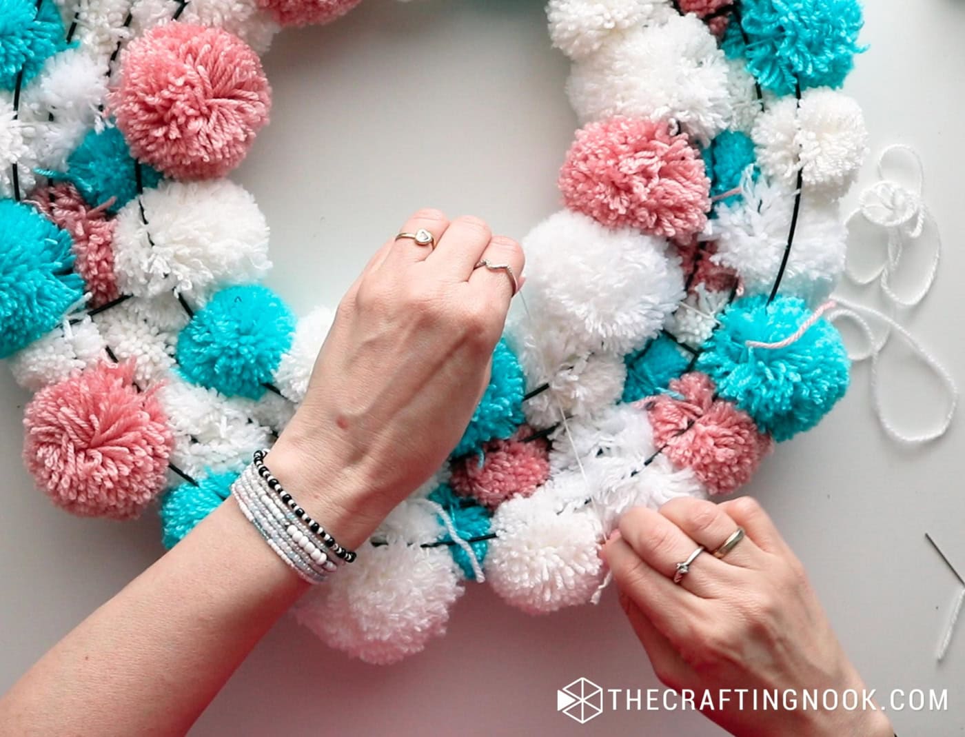 image above adjusting the ornaments placed in front on the back of the pompom garland
