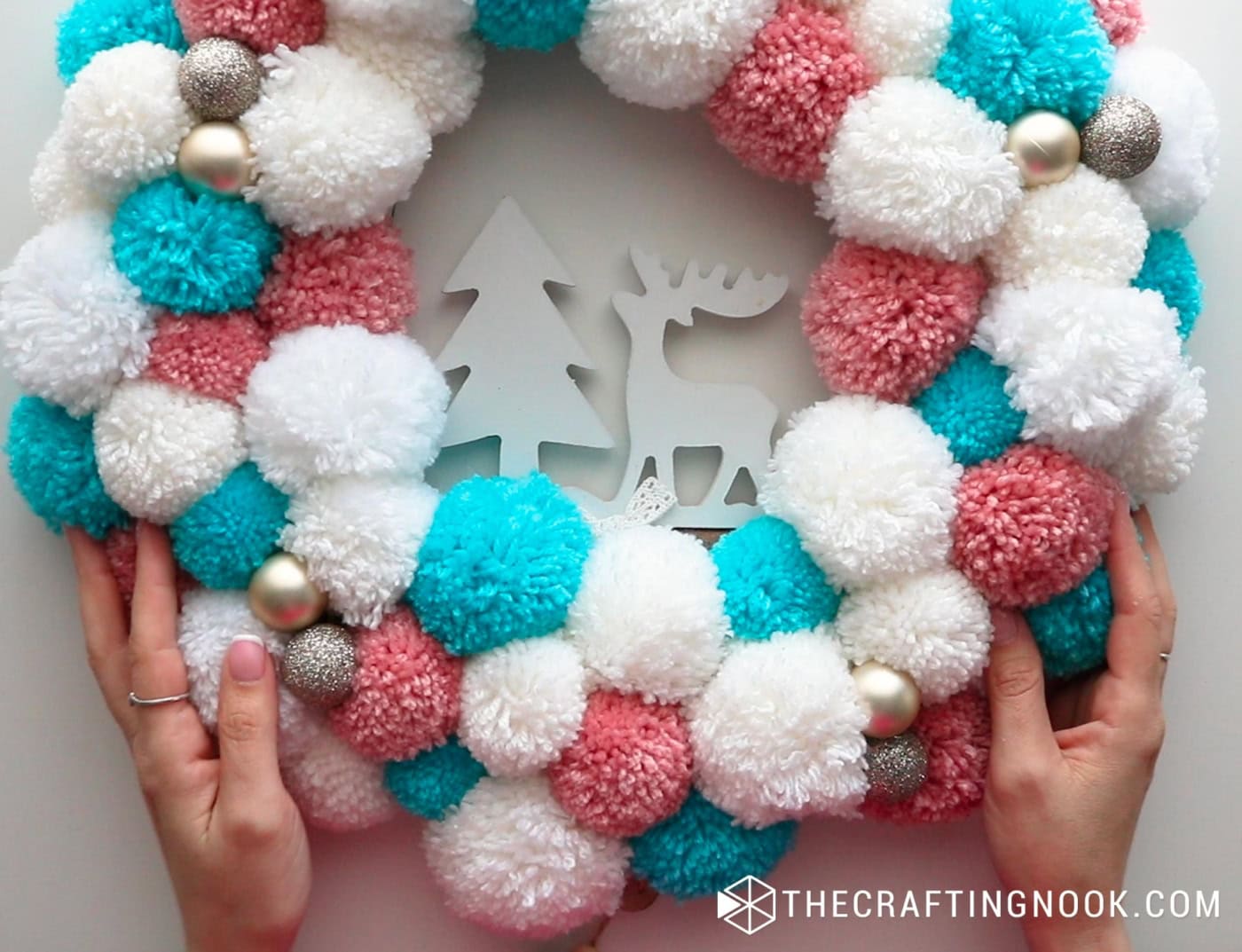 close up image of the pompom garland with the deer hanger in the center already placed
