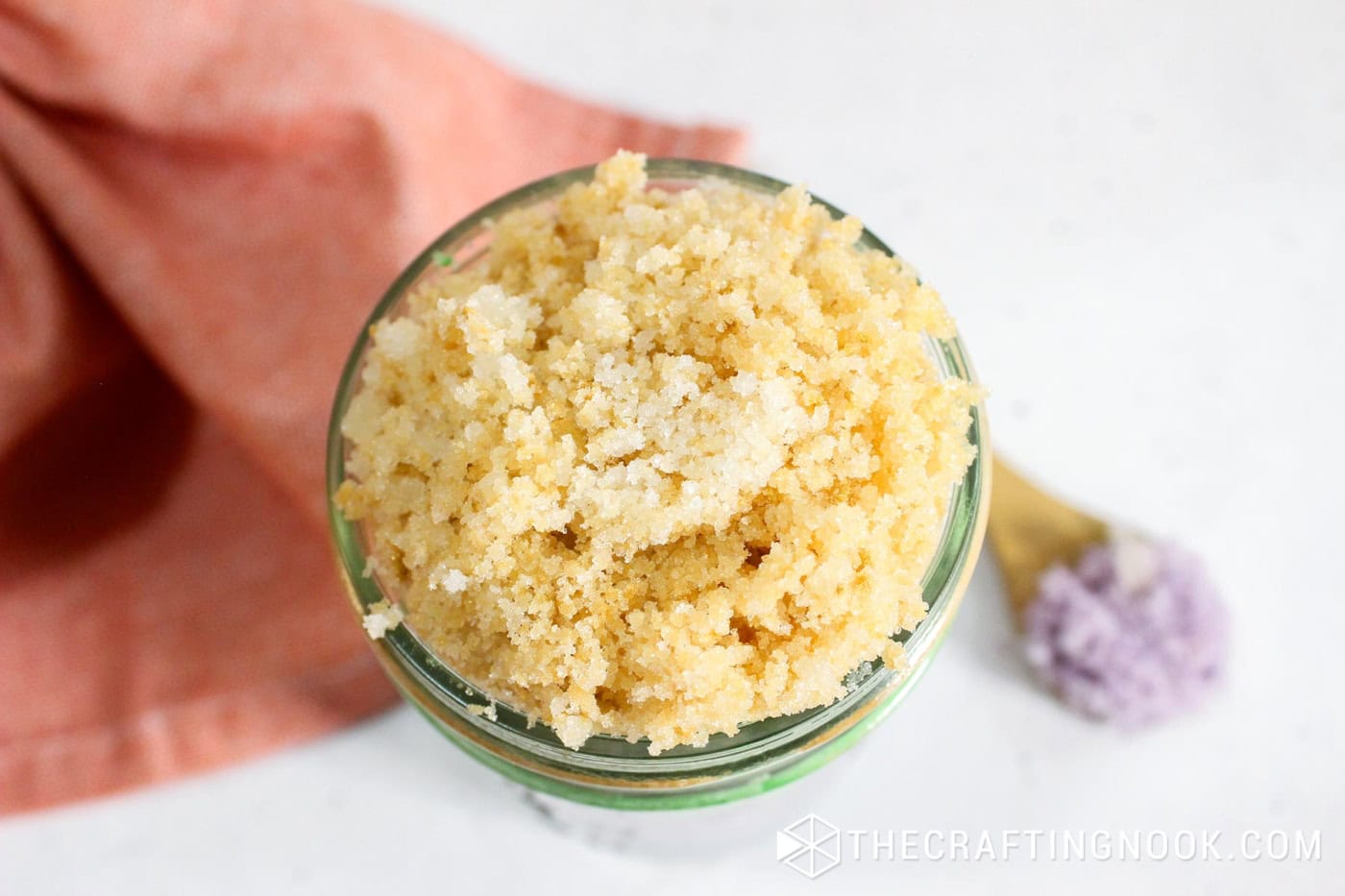 Overhead view of the jar layers of sugar scrub in different pastel colors, blue, purple, green and yellow.