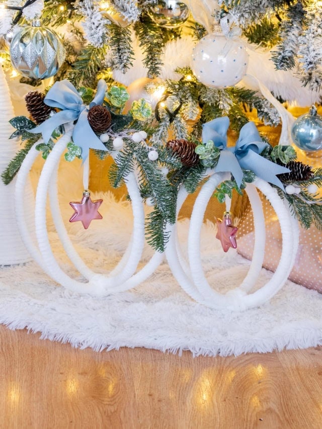 Two completed large hoop ornaments displayed under a Christmas tree decorated in whites, pinks, blues, and greenery. Feature image