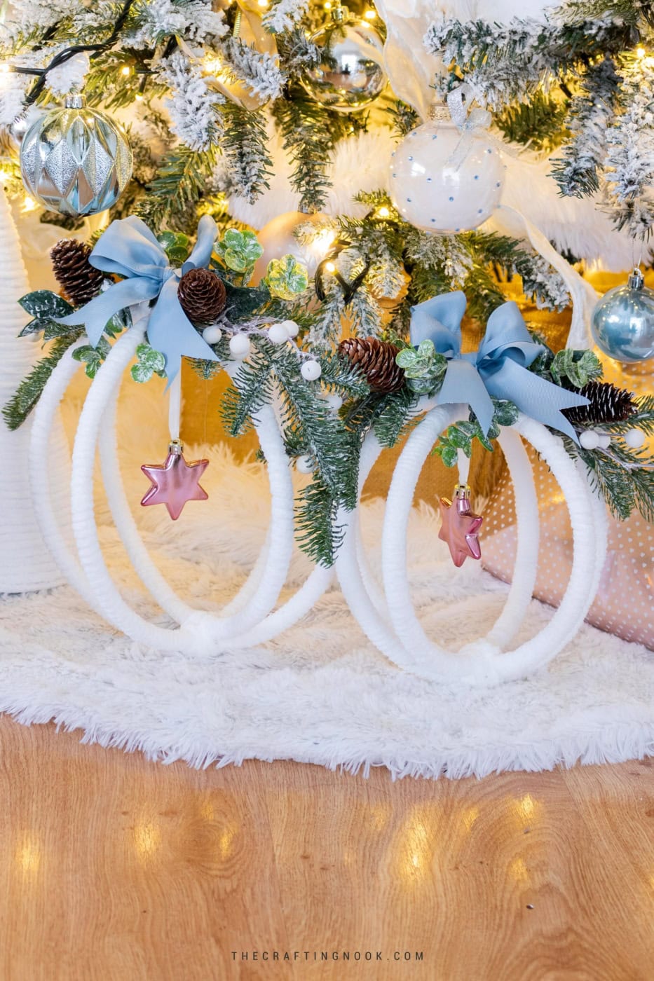Two completed large hoop ornaments displayed under a Christmas tree decorated in whites, pinks, blues, and greenery. Feature image