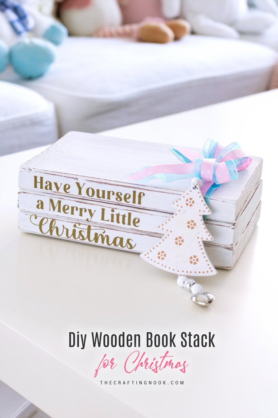 Angled view of the Christmas wooden book stack with gold lettering, pastel bow, and tree ornament on a white table. Featured image with title overlay