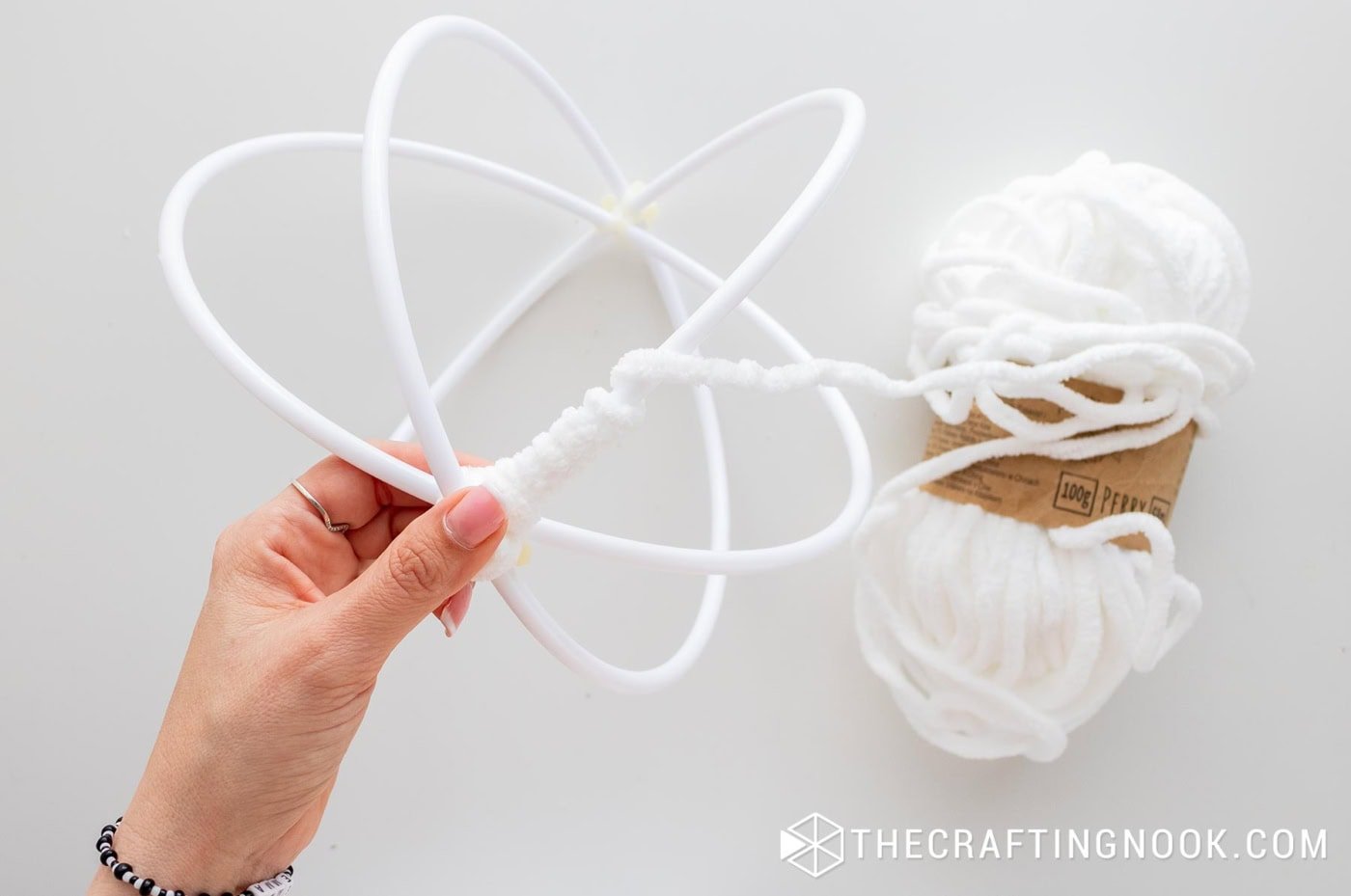 Beginning to wrap the first section of the hoop with white chenille yarn.