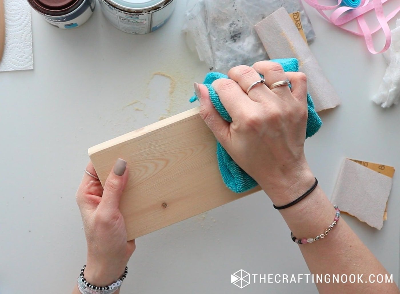 Cleaning sanding dust off the wood block with a turquoise cloth.