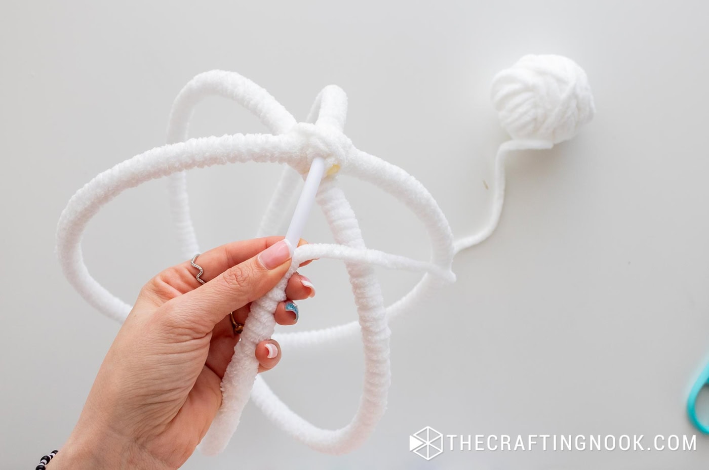 Close-up of wrapping the final hoop section with chenille yarn near the top joint.