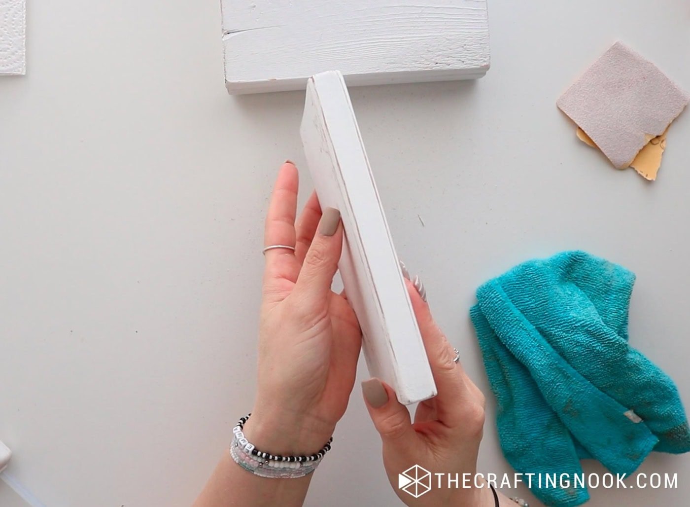 Lightly sanding the painted block to distress the edges.