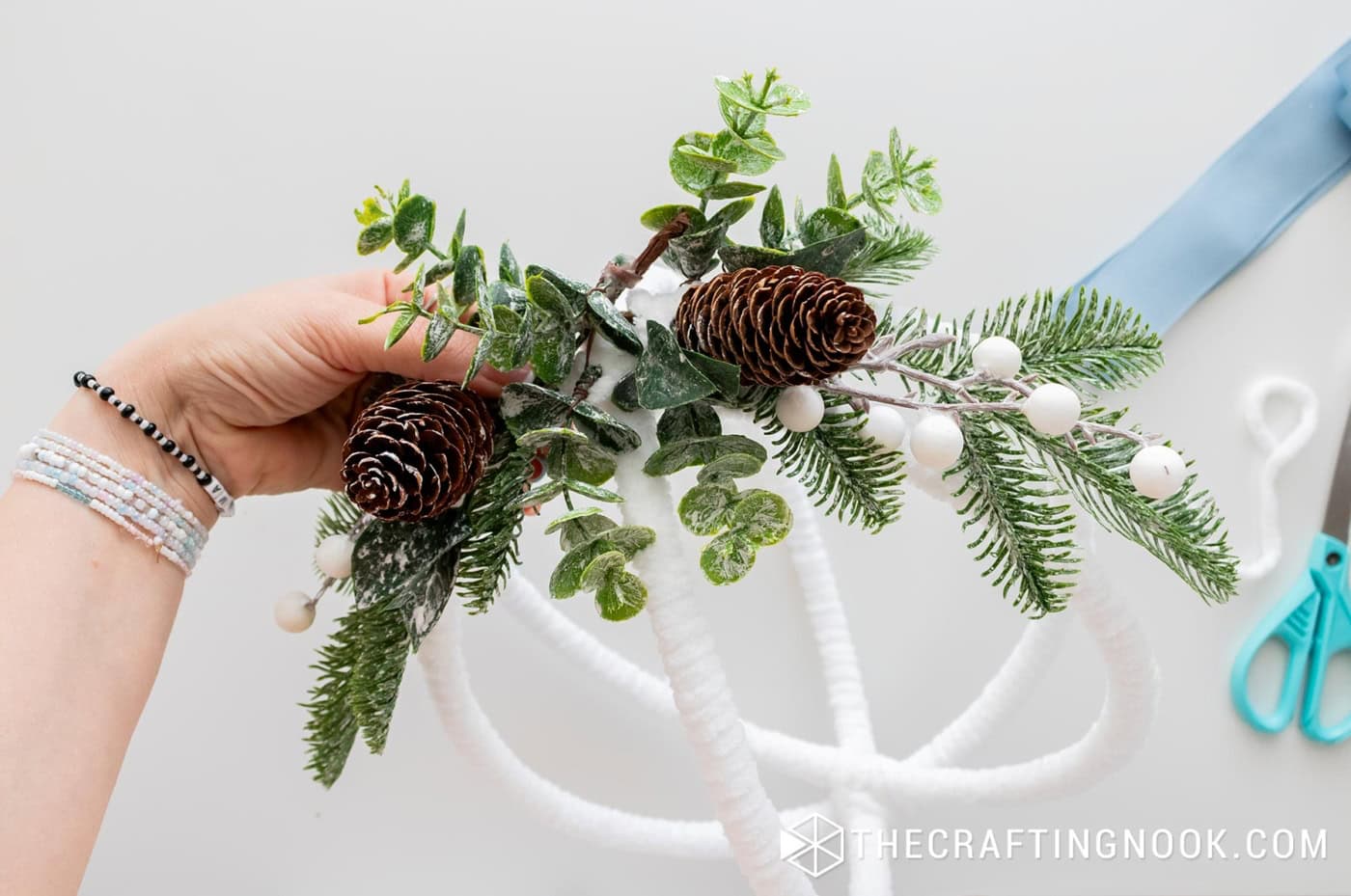 The greenery section fully secured, showing pine branches, eucalyptus, berries, and pinecones.