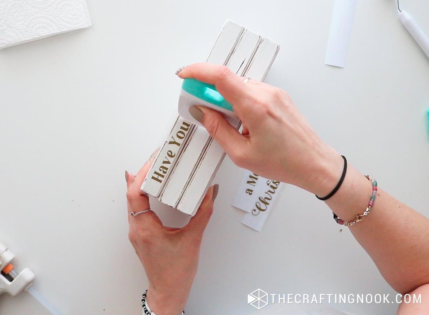 Applying the vinyl words onto the wood book spine using a scraper tool.