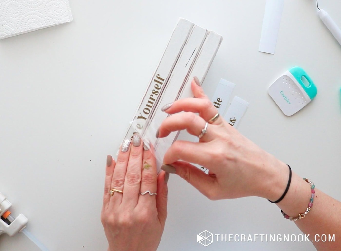 Peeling back transfer tape to reveal the vinyl lettering on the wood.