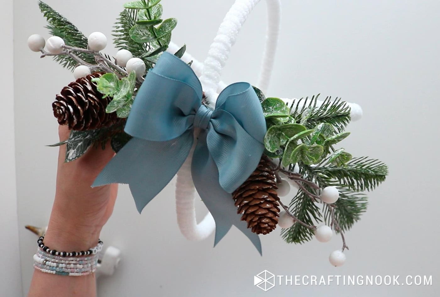 The ornament with the blue bow already attached on top of the greenery cluster.
