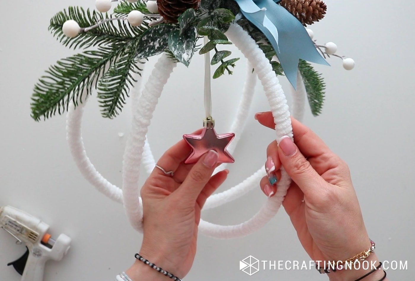 Adjusting the placement of the hanging pink star ornament inside the finished hoop.