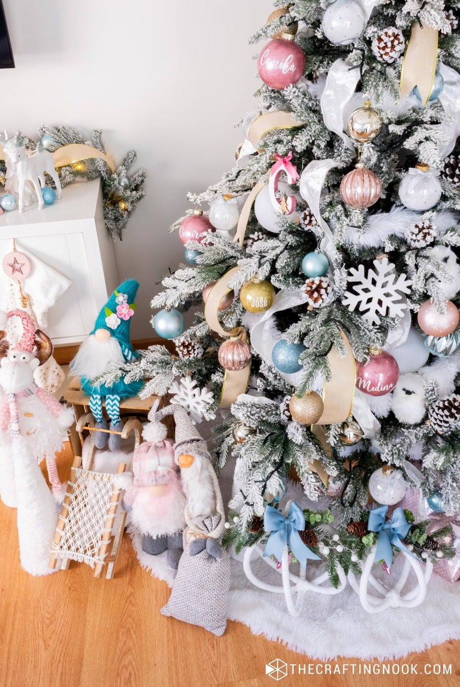 Shiny blue ornament on a flocked Christmas tree paired with soft pink, gold and white decorations.