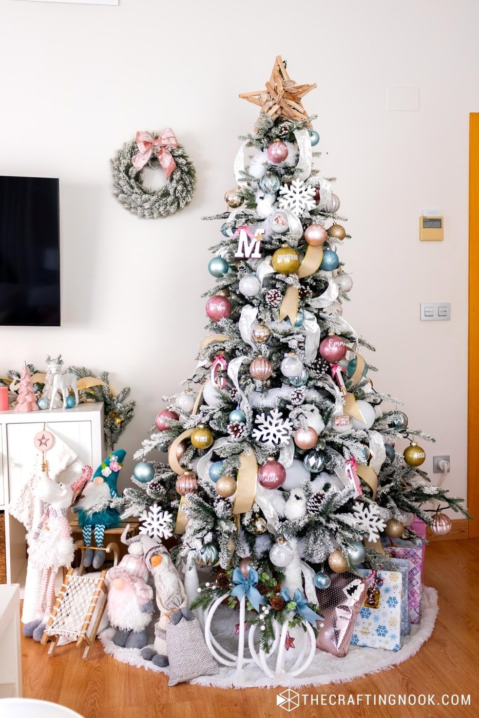 Handmade glitter ornament with a name on vinyl placed among flocked branches and soft ribbon.