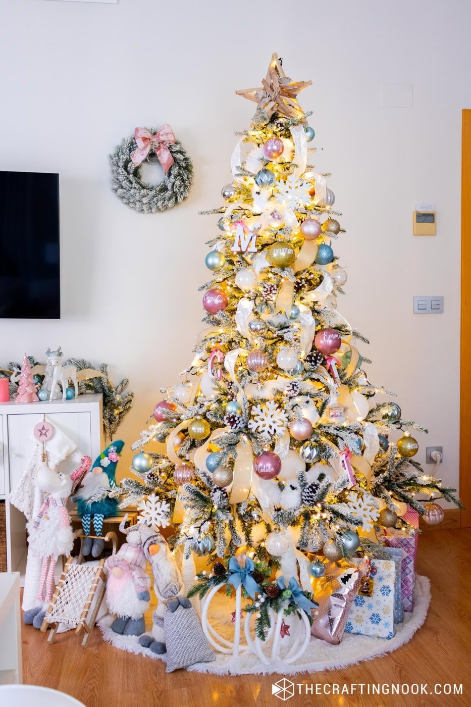 Close-up of a glitter personalized ornament hanging on a flocked Christmas tree with gold ribbon.