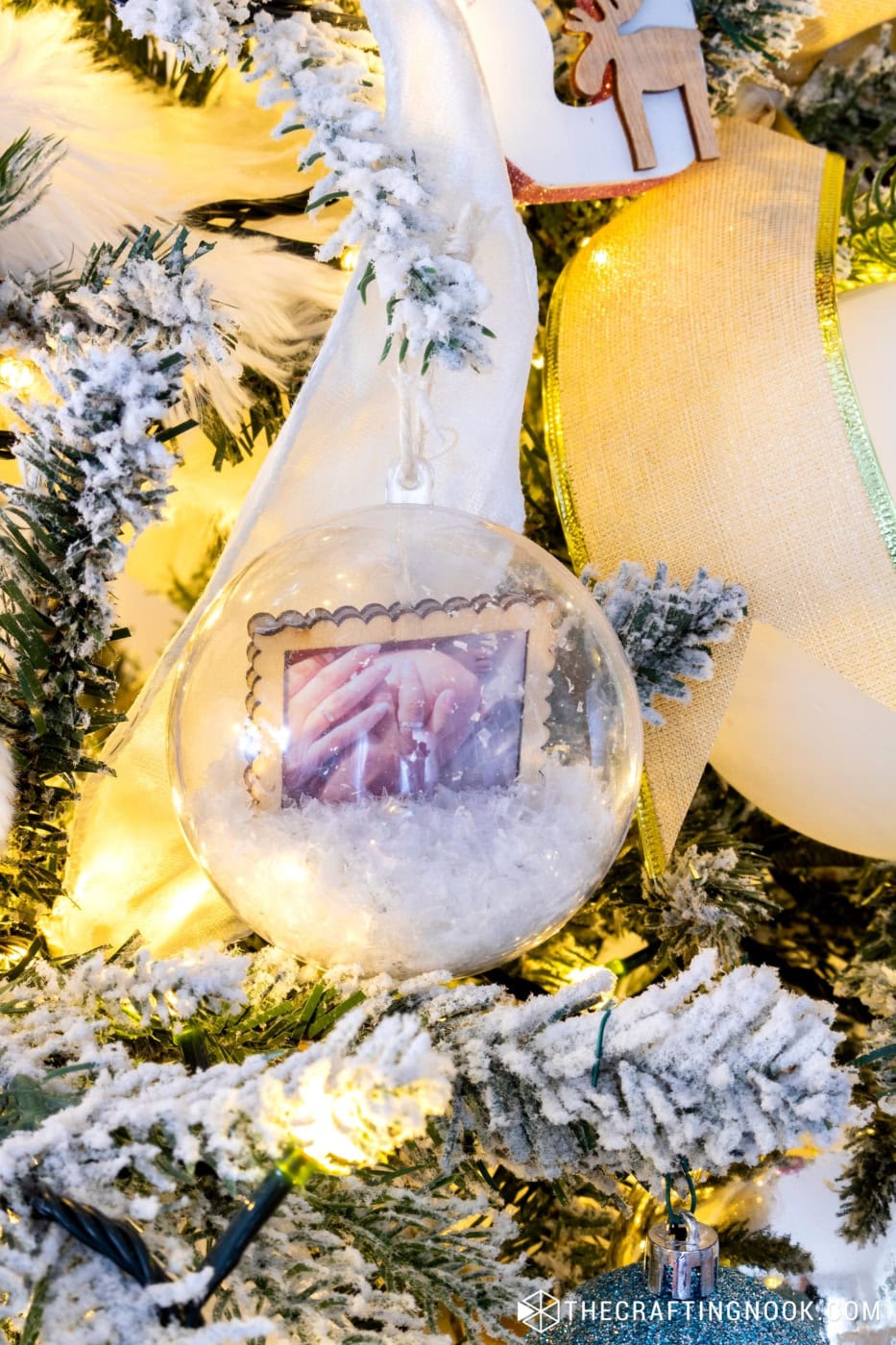 Memory keepsake snow-globe ornament with faux snow and a family photo hanging on the Christmas tree.