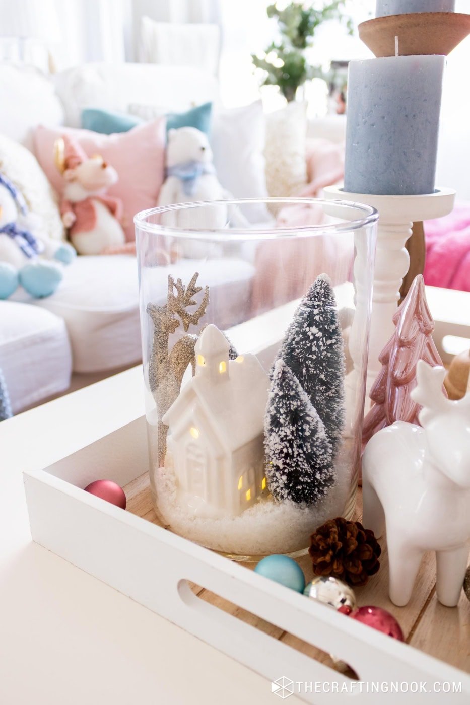 Winter scene jar styled on a table with ornaments, lights, and surrounding holiday decorations.