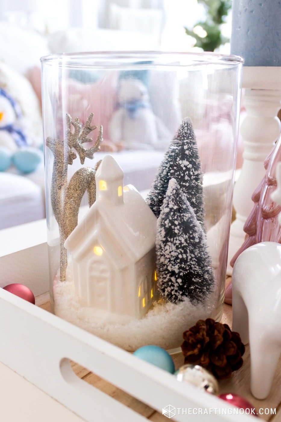 Closeup view of the jar winter scene showing the house, trees, and snowy base through the glass.