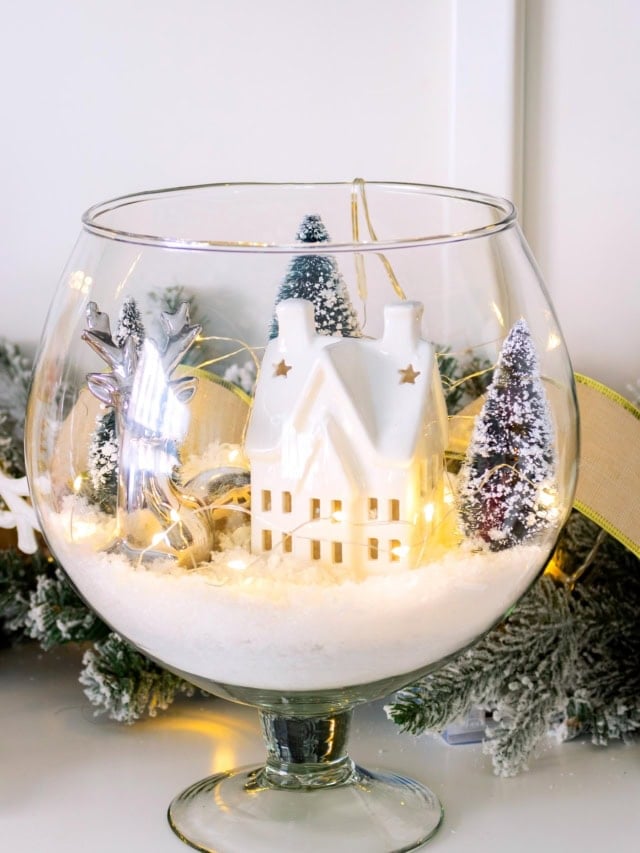 Finished winter scene in a glass vase displayed on a wooden surface with surrounding decor. Feature image.