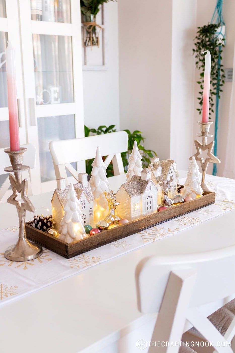 Side view of the winter village tray centerpiece with ceramic houses, trees, and fairy lights.