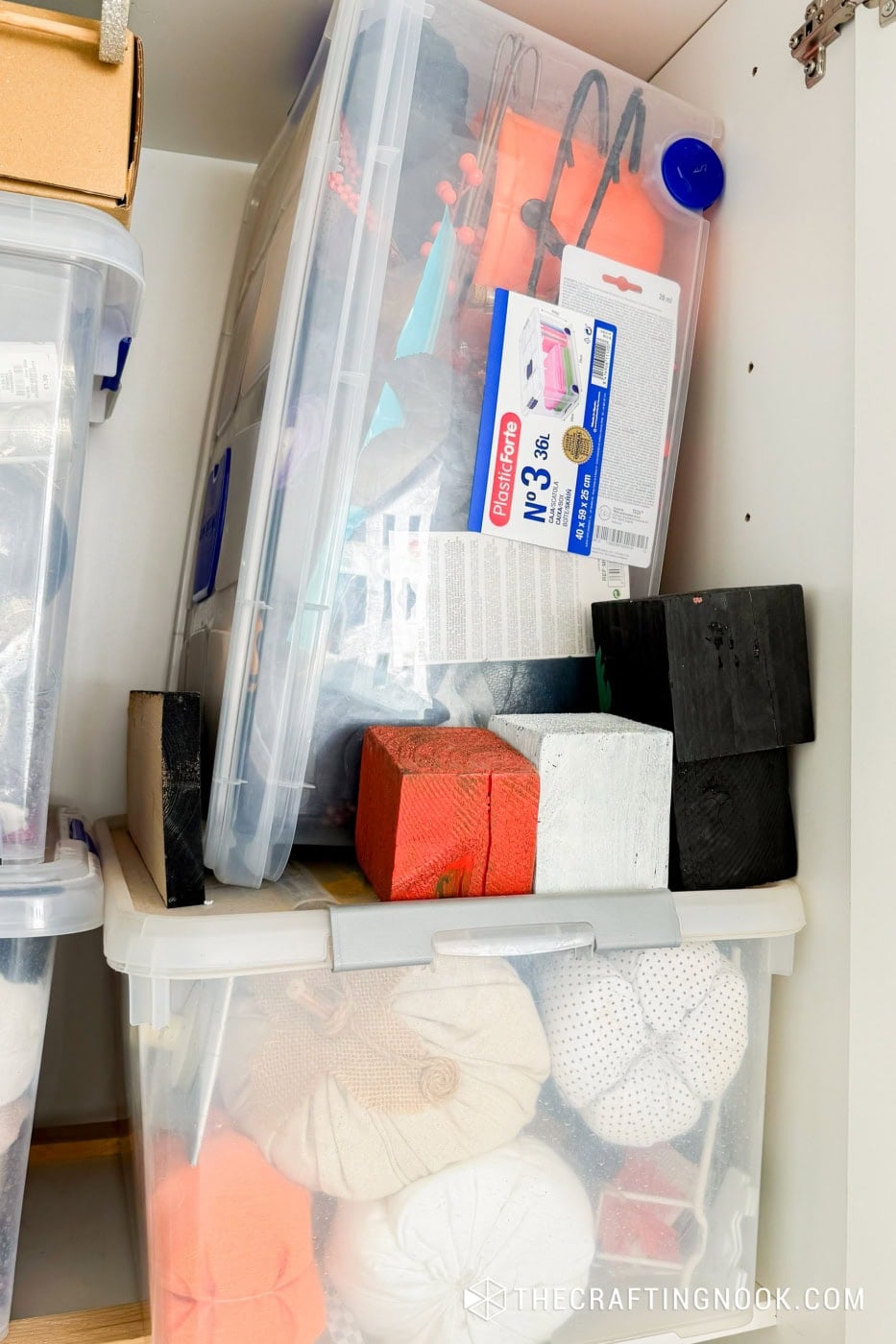 Clear plastic storage bin with craft tools, paints, and supplies for seasonal decor.