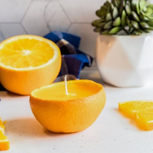 Citrus peel candle made from orange peel with lemon slices in the background.